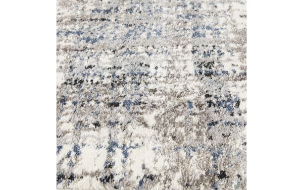 Plush area rug with a high-pile texture featuring a modern abstract pattern in shades of gray, blue, black, and white.