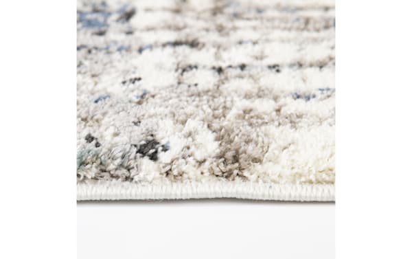 Close-up of a soft, plush area rug with a thick pile featuring a neutral beige and white geometric pattern, ideal for cozy home decor.