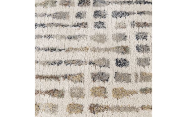 Soft, plush area rug with a textured cream background and abstract rectangular patterns in muted gray, beige, and gold tones, suitable for modern home decor.