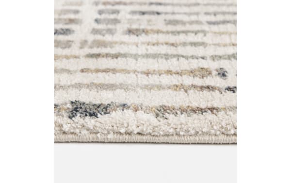 Close-up of a beige and cream textured area rug with a soft, plush pile and subtle multicolor geometric pattern, ideal for living room decor.