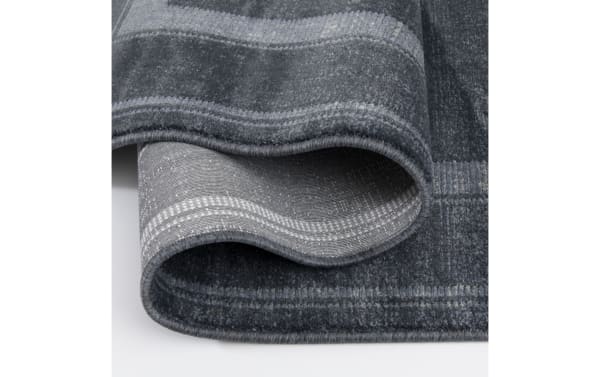 Dark gray and light gray checkered area rug with a soft, textured surface and tightly stitched edges, showing the underside weave pattern.