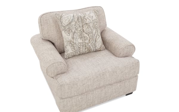 Beige fabric armchair with rolled arms and a patterned beige and gray decorative throw pillow, featuring a soft, textured upholstery.
