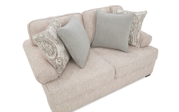 Light beige fabric loveseat with rounded armrests, featuring two patterned and two solid gray decorative throw pillows, modern style.