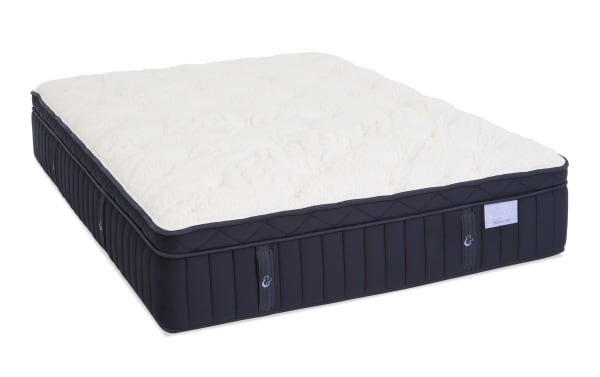 Luxury mattress with quilted white top and dark blue sides, featuring vertical stitching and fabric handles. Brand label reads "Crescent & Cloud, Medium Firm."