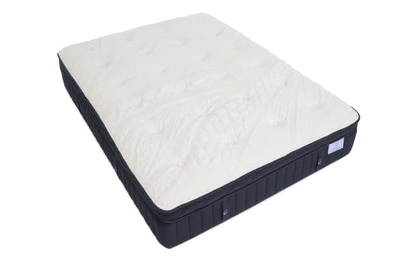 Mattress with a white quilted, textured top and dark blue sides, featuring a plush pillow-top design for enhanced comfort and support.