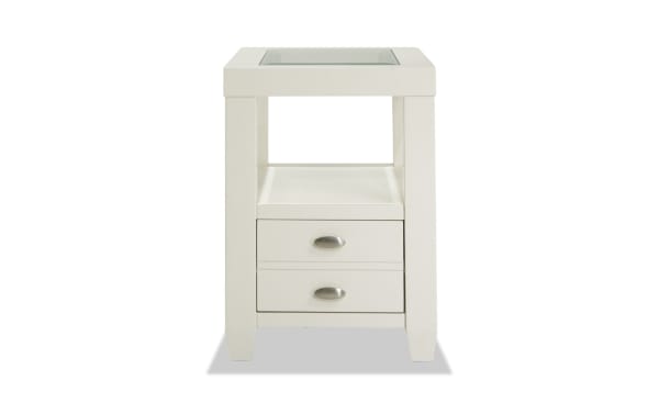 Prestige White Storage Chairside Table from Prestige Occasional collection, transitional style with solid acacia, MDF, glass top, beveled edges, oval metal handles, one drawer, open shelf, and built-in USB/power outlets for device charging.