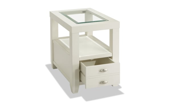 Prestige White Storage Chairside Table from Prestige Occasional collection, transitional style with solid acacia, MDF, beveled tempered glass top, oval metal handles, open shelf, and power outlets for device charging.