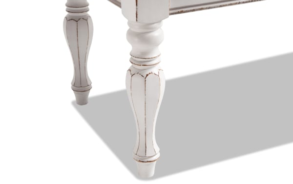 White distressed farmhouse-style turned wood legs of the Scarlett White Storage Bench in taupe, made from birch veneers and poplar solids.