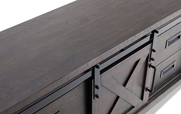 Montana 65'' brown rustic TV stand with pine solids, MDF, and pine veneer, featuring sliding barn door, black metal hardware, shelves, and drawers for media storage.