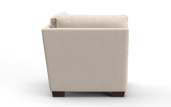 Beige fabric armchair with a cushioned backrest, wooden block legs, and a modern, boxy design shown from the side.