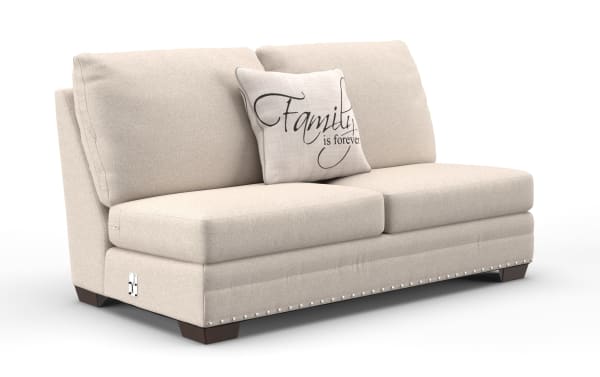 Beige fabric loveseat sofa with dark wooden legs, nailhead trim along base, two large back cushions, and a decorative pillow reading "Family is forever."