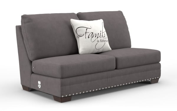 Gray fabric loveseat sofa with plush cushions and dark wooden legs, featuring a decorative white pillow with the text "Family is forever" and silver nailhead trim along the base.