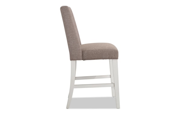 Montana Dining rustic counter height stool with beige polyester fabric upholstery, memory foam seat, and white rubberwood frame.