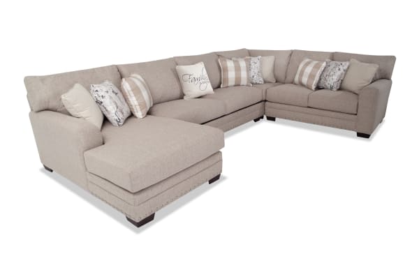 Cottage Chic Beige 150'' 4 Piece Left Arm Facing Chaise Sectional in traditional style with beige polyester fabric, nailhead trim, and 10 patterned accent pillows.