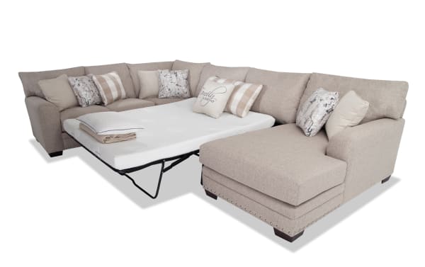 Cottage Chic Beige 4-piece right arm facing sleeper chaise sectional with queen gel memory foam mattress, beige polyester fabric, nailhead trim, and multiple accent pillows.