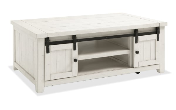 Rustic Montana White Storage Coffee Table with pine solids, plywood, gliding barn doors, black hardware, and casters for easy mobility.