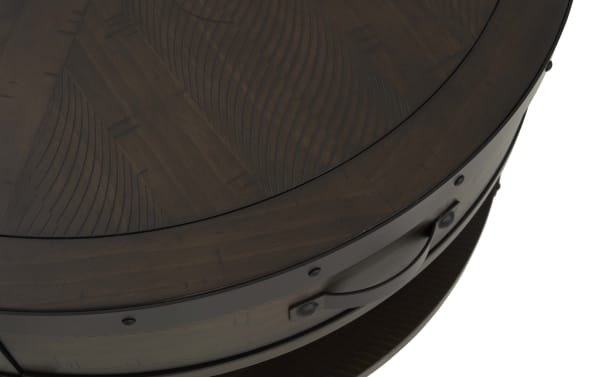 Dark brown wooden round table with decorative carved pattern on the top surface, featuring metal rivet accents and a curved handle on the side.