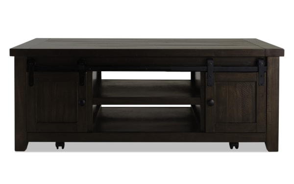 Rustic Montana Brown Storage Coffee Table from Montana Entertainment & Occasional collection, made of pine solids and plywood, featuring dark brown finish, gliding barn doors with black metal hardware, open shelves, and casters for mobility.