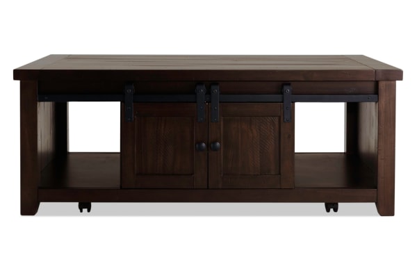 Rustic Montana Brown Storage Coffee Table from Montana Entertainment & Occasional collection, made of pine solids and plywood, featuring dark brown finish, gliding barn doors with black metal hardware, open shelving, and casters for mobility.