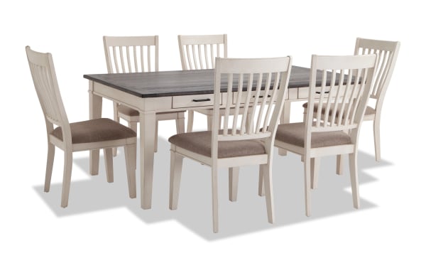 Montana 7 Piece White & Beige Upholstered Dining Set with rustic rubberwood and oak veneer table, six fabric polyester cushioned chairs, and storage drawers.