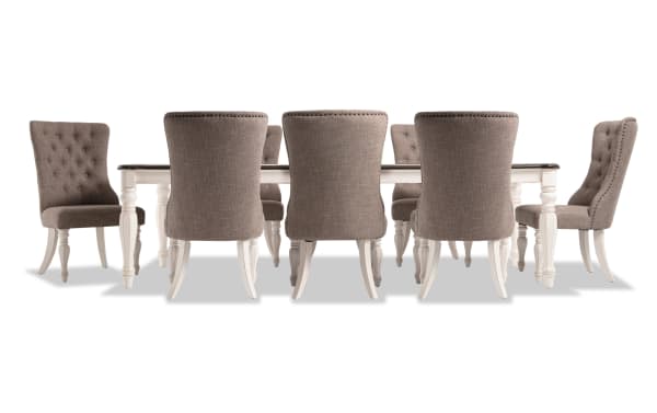Scarlett 9 Piece Cottage Dining Set with beige polyester upholstered tufted chairs, extendable white distressed oak table with carved legs, and oak veneer top.