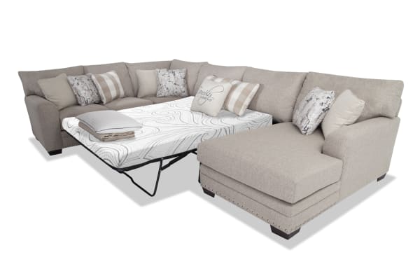 Cottage Chic Beige 4-piece left arm facing sleeper chaise sectional with queen cooling Bob-O-Pedic memory foam mattress, polyester fabric upholstery, nailhead trim, and ten accent pillows.