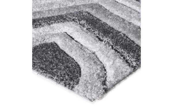 Shaggy area rug with a soft, plush texture featuring a modern geometric pattern in varying shades of gray and white.