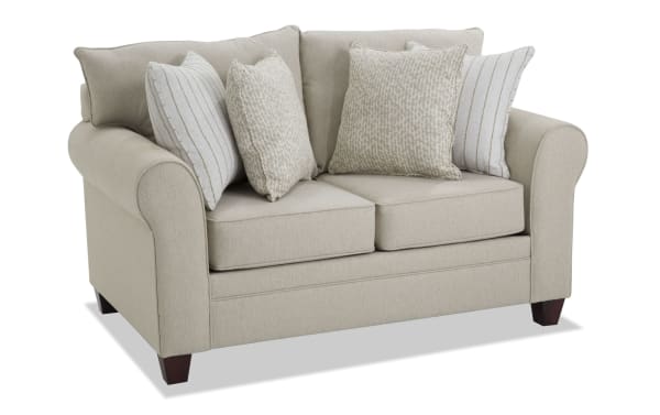 Beige Laurel 65'' loveseat with transitional style, rolled arms, plush Bob-O-Pedic memory foam cushions, and four patterned accent pillows in polyester fabric upholstery.