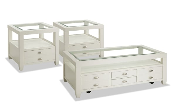 Prestige White Storage Coffee & 2 End Table Set from Prestige Occasional collection, transitional style with white solid acacia, MDF, and tempered glass tops. Features beveled glass edges, display shelves, spacious storage drawers, dual-access drawers, removable serving trays, and coffee table casters for easy mobility.