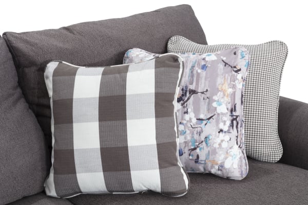 Gray fabric throw pillows with plaid, floral, and houndstooth patterns on Cottage Chic Gray 150" traditional polyester sectional sofa.