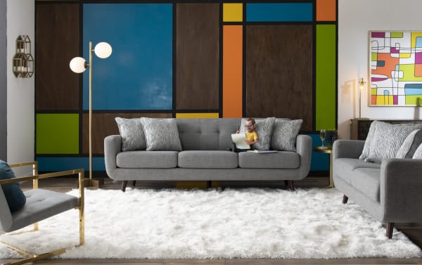 Mid-century modern Bettie Gray 65'' Loveseat in gray polyester fabric with tufted seat back, four patterned accent pillows, track arms, and wooden legs.