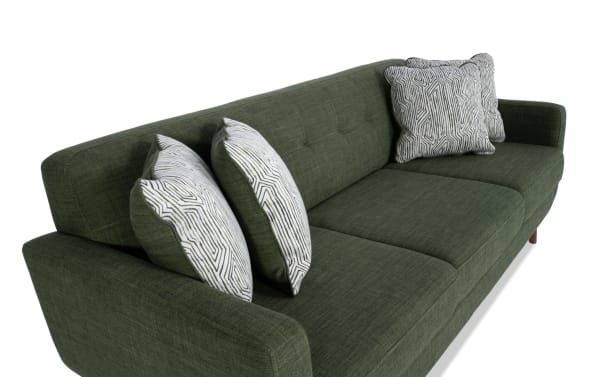 Bettie Avocado 86'' Sofa in green polyester fabric with mid-century modern tufted back, track arms, wooden legs, and four patterned accent pillows.