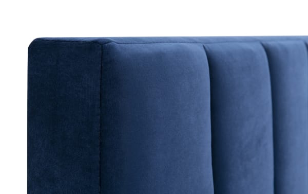 Blue upholstered panel headboard of the Aster Full Blue Upholstered Panel Bed, featuring vertical tufting and soft polyester fabric in a transitional style.