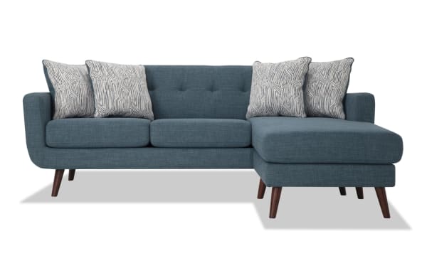 Bettie Teal 86'' Chofa mid-century modern sectional sofa in blue polyester fabric with tufted back, four patterned pillows, and wooden tapered legs.