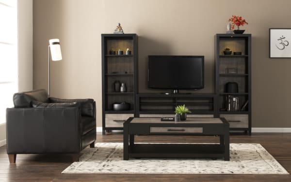 Fusion 108'' Black & Gray 3 Piece Storage Entertainment Center from Fusion Entertainment & Occasional collection, transitional style with poplar solids, MDF, and birch veneers. Features two-tone finish with bar handle hardware, adjustable shelves, touch-activated LED lighting in piers, and cord management opening for organized media storage. Includes TV stand, two tall storage piers with drawers, and a matching coffee table on a patterned rug.