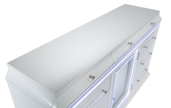 Glamour White 9 Drawer Dresser in pearly white with acacia veneers, MDF, mirror, and plywood. Features LED three-way touch lighting, mirrored crystal trim, acrylic and silver hardware, nine drawers with felt and cedar lining, and adjustable shelving in center cabinet. Glamour Bedroom collection, glam style.