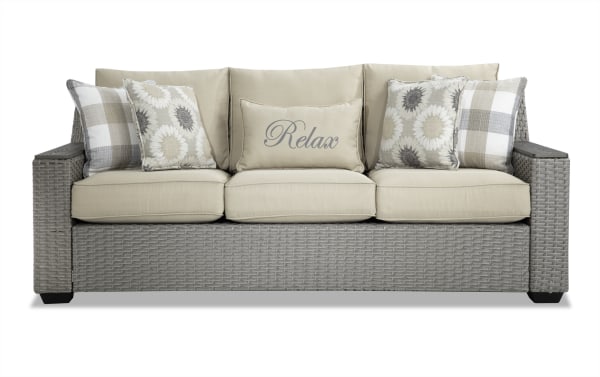 Cottage Chic Beige Wicker Outdoor Sofa with beige polyester cushions, floral and plaid accent pillows, rust-proof aluminum frame, and memory foam seating.