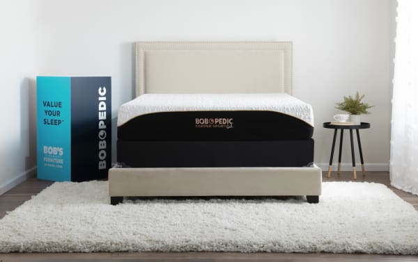 Copper Sport Gel 11.5'' Twin XL Firm Standard Mattress Set by Bob-O-Pedic with temperature-regulating copper gel memory foam, black and white cover, beige upholstered bed frame, and modern bedroom setup.