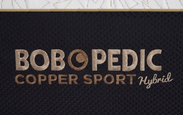BOB-O-PEDIC Copper Sport Hybrid mattress logo embroidered in copper and beige on black fabric, highlighting Copper Sport collection branding.
