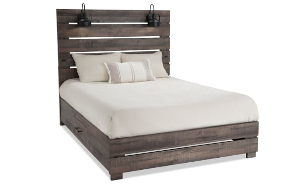 Rustic Foundry Queen Brown Storage Platform Bed with paneled slat MDF wood grain frame, black headboard lamps, and USB charging port.