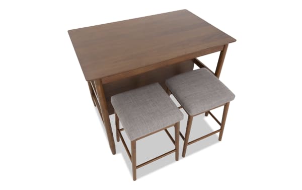 Mid-century modern wooden dining table set with two gray fabric cushioned stools, compact design for small spaces.