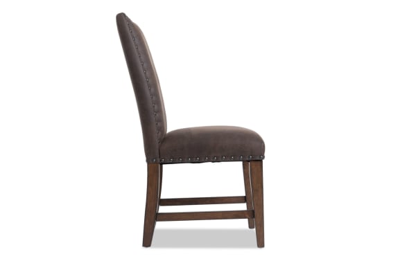 Canyon Brown faux leather dining chair with solid back, nailhead trim, and wooden legs, featuring rustic style and memory foam seat.