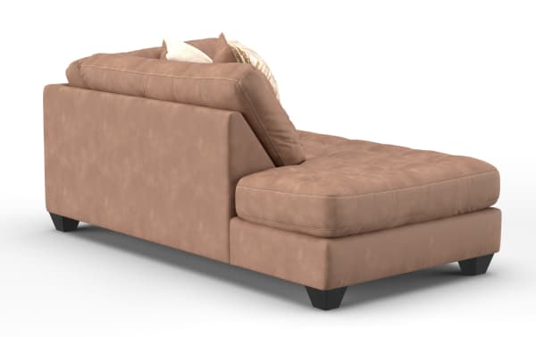 Modern tan leather chaise lounge sofa with tufted seat cushion, angled backrest, and decorative pillows, featuring dark wooden legs.