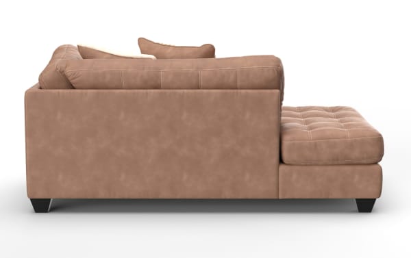 Modern sectional sofa in light brown suede with tufted cushions, plush back pillows, and black tapered wooden legs, shown from the side.
