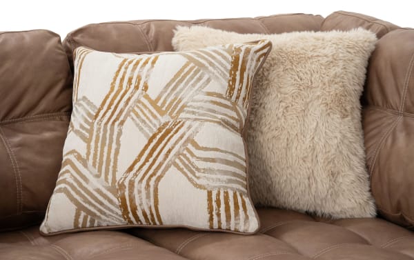 Two decorative accent pillows on a cognac brown Sierra transitional sectional sofa, featuring tufted polyester fabric and plush textures.