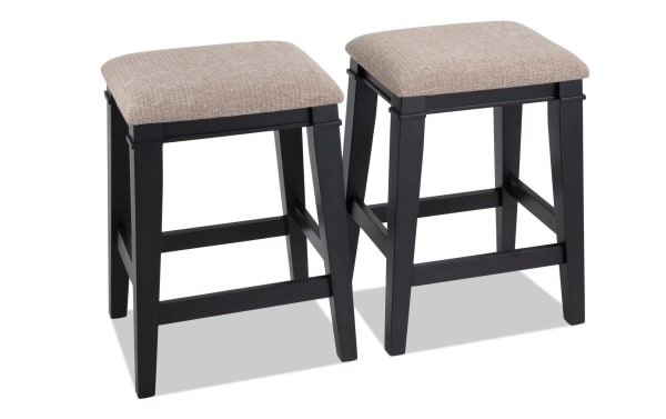 Set of 2 Montana Black & Beige Backless Upholstered Counter Height Stools with beige polyester fabric seats, rustic wooden MDF frames, and memory foam padding.