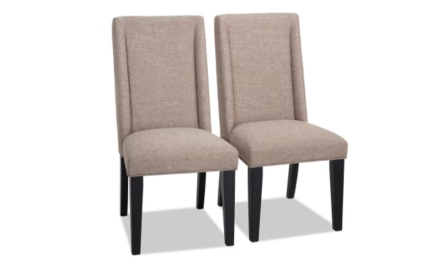 Set of 2 Montana Dining rustic chairs with beige polyester fabric upholstery, solid back, black MDF legs, and memory foam seats for comfort.