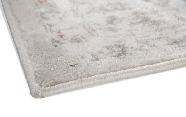 Close-up of the Emery 5' x 8' Multi Floral Rug corner, showing soft polypropylene fabric with multicolored floral patterns and tightly stitched edges.