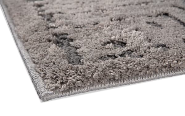 Gray geometric transitional rug corner close-up showing soft polypropylene fabric texture and detailed edge stitching of Stonington 5' x 7' area rug.