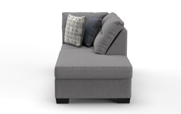 Gray fabric sectional sofa with tufted back cushions and three decorative pillows in blue and patterned designs, modern style seating.